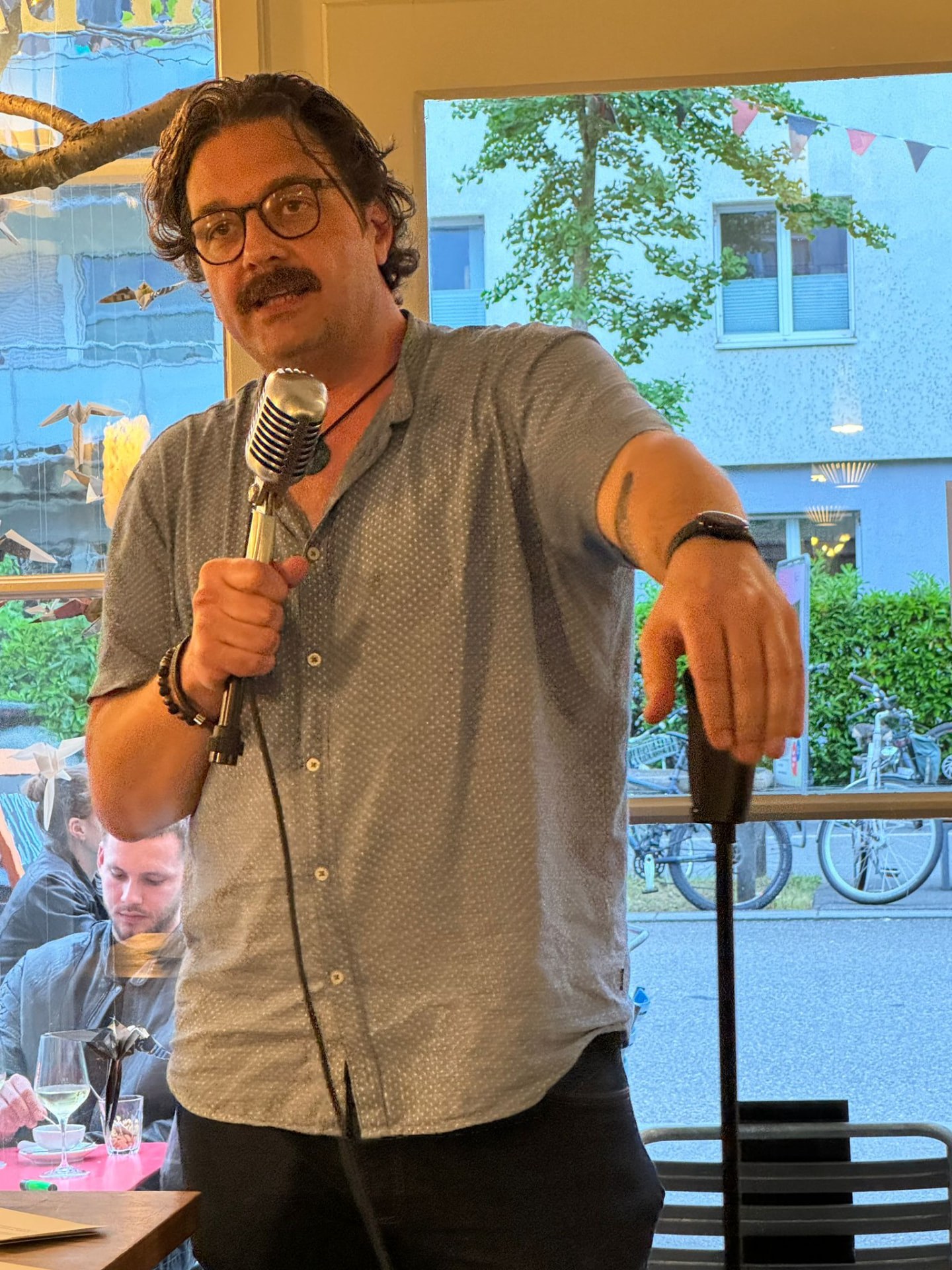 Urs Kloter mit Mikrofon vor einem grossen Fenster